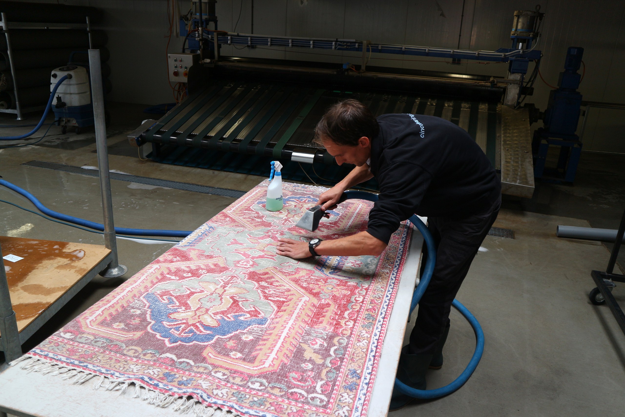 Vakspecialist behandelt vlekken op een Perzisch vloerkleed in de wasserij